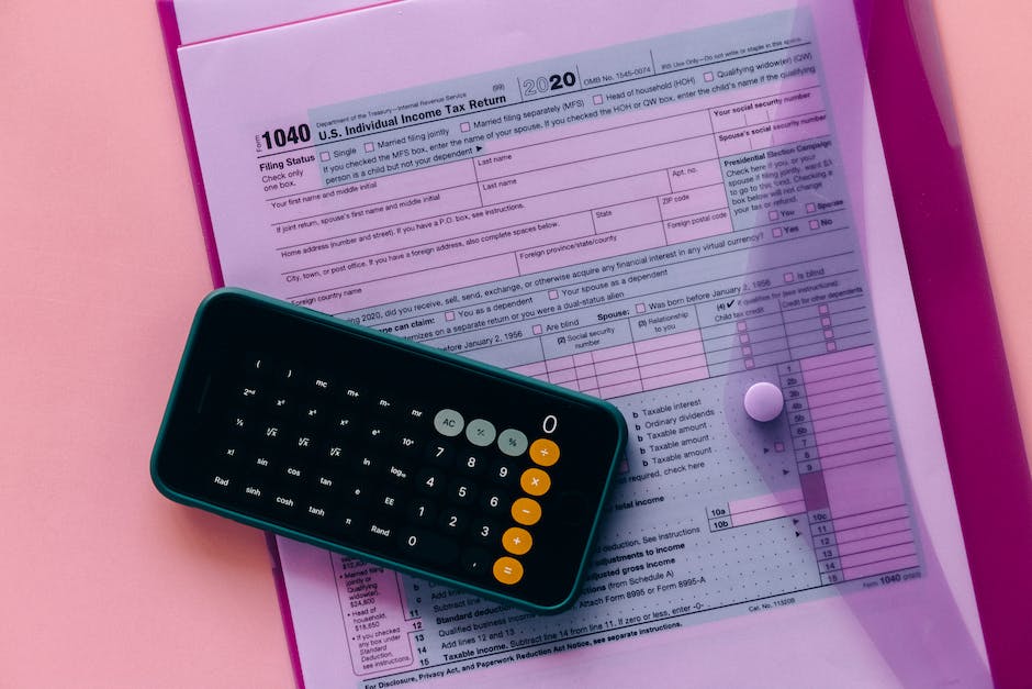 Image of a person holding a budget worksheet with a calculator, pens, and coins, symbolizing financial management and planning.