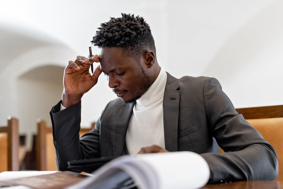 A businessman sitting in front of a computer with his hand on his chin, contemplating ethical and legal aspects of drop shipping.