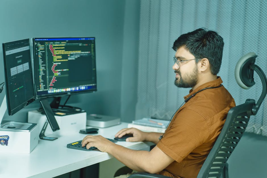 A software developer working remotely with multiple screens displaying code